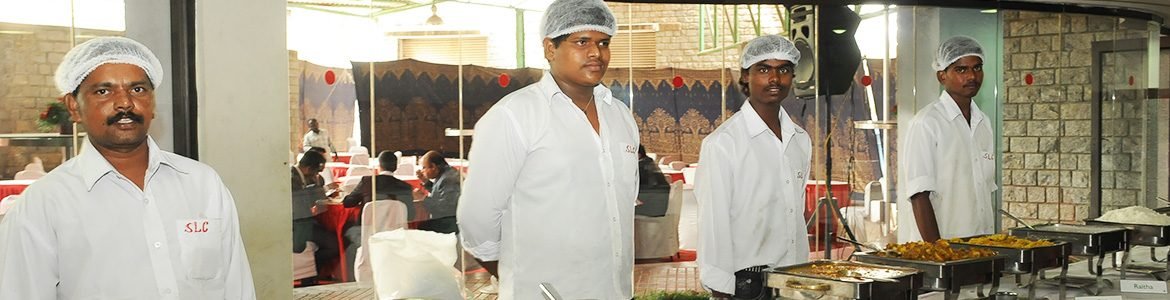 Sri Lakshmi Caterers staff in branded shirts and hairnets serving a buffet in Bangalore