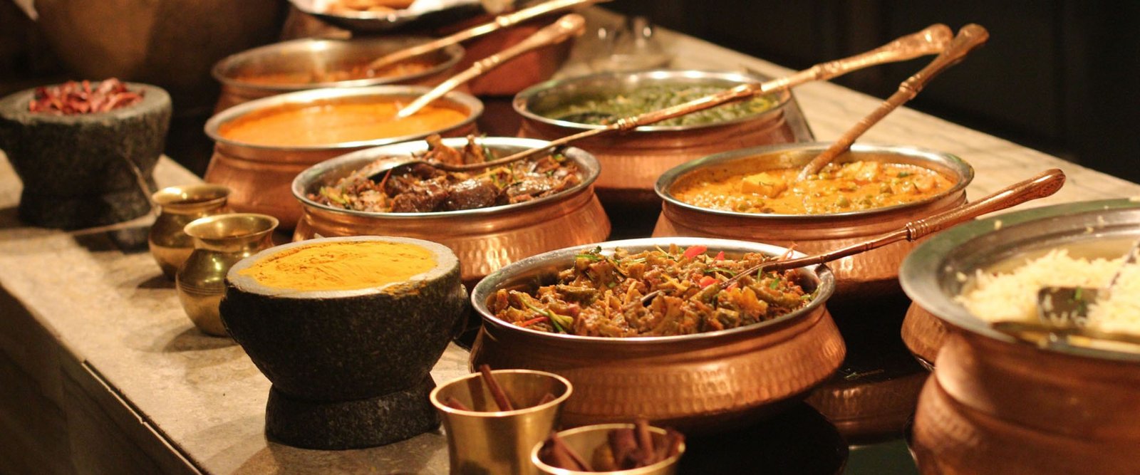 Wedding buffet counter with food served from traditional copper pots
